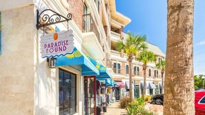 Una calle con una hilera de tiendas, incluyendo una con un cartel que dice 'Paradise Found'.