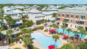 Zona residencial con piscina rodeada de palmeras y sillas de descanso.