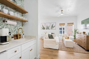 A modern kitchen with white cabinets, a coffee machine, and a patterned backsplash.