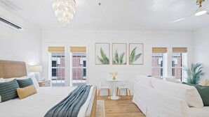 Una habitación de hotel moderna con una cama grande, un sofá, una mesita y vistas a la ciudad.