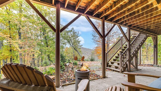 A covered outdoor seating area with wooden chairs and a fire pit, surrounded by trees and a staircase. - Secluded Mtn-view Retreat in Mars Hill (Mars Hill)