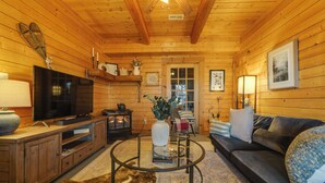 A wooden cabin interior with a television, sofa, and a glass coffee table. - Secluded Mtn-view Retreat in Mars Hill (Mars Hill)