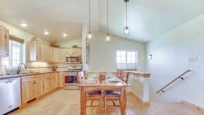 Cozinha ampla com armários de madeira, mesa de jantar com cadeiras e luminárias pendentes.