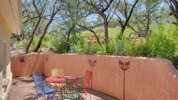 An outdoor patio with a table and chairs, surrounded by a wall with decorative animal motifs.