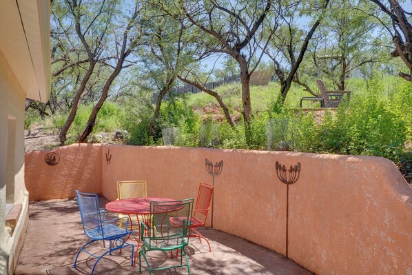 An outdoor patio with a table and chairs, surrounded by a wall with decorative animal motifs. - Peaceful & Historic Home in Patagonia! (Patagonia)