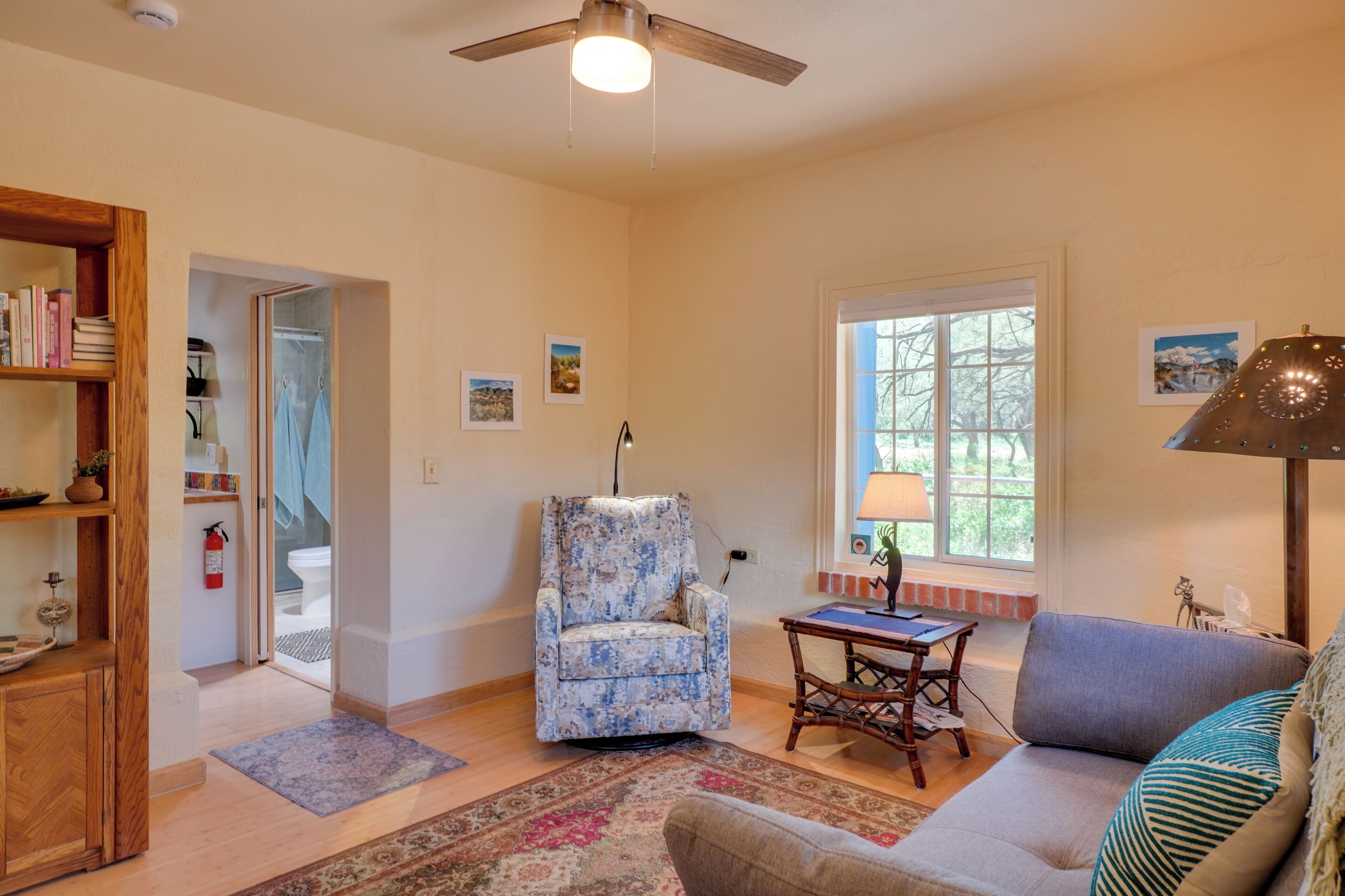 A living room with a ceiling fan, a sofa, a chair, a table, and a bookshelf.