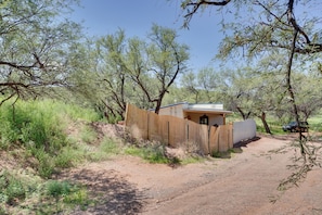 A small building with a fenced entrance, surrounded by trees and a dirt path. - Peaceful & Historic Home in Patagonia! (Patagonia)
