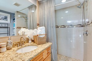 A bathroom with a granite countertop sink, a mirror, a shower with a glass door, and a wicker basket with towels. - 8 Mi to Sunset Beach: Home w/ Large Patio + Pool! (New Port Richey)