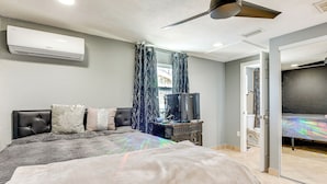 Une chambre à coucher comprenant un lit, un ventilateur de plafond, un appareil de climatisation, une télévision et une armoire.