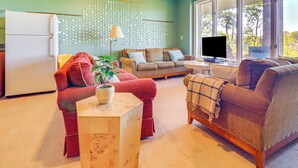 Ein Wohnzimmer mit einer Couch, einem roten Sessel, einem Holztisch und einem Fernseher.