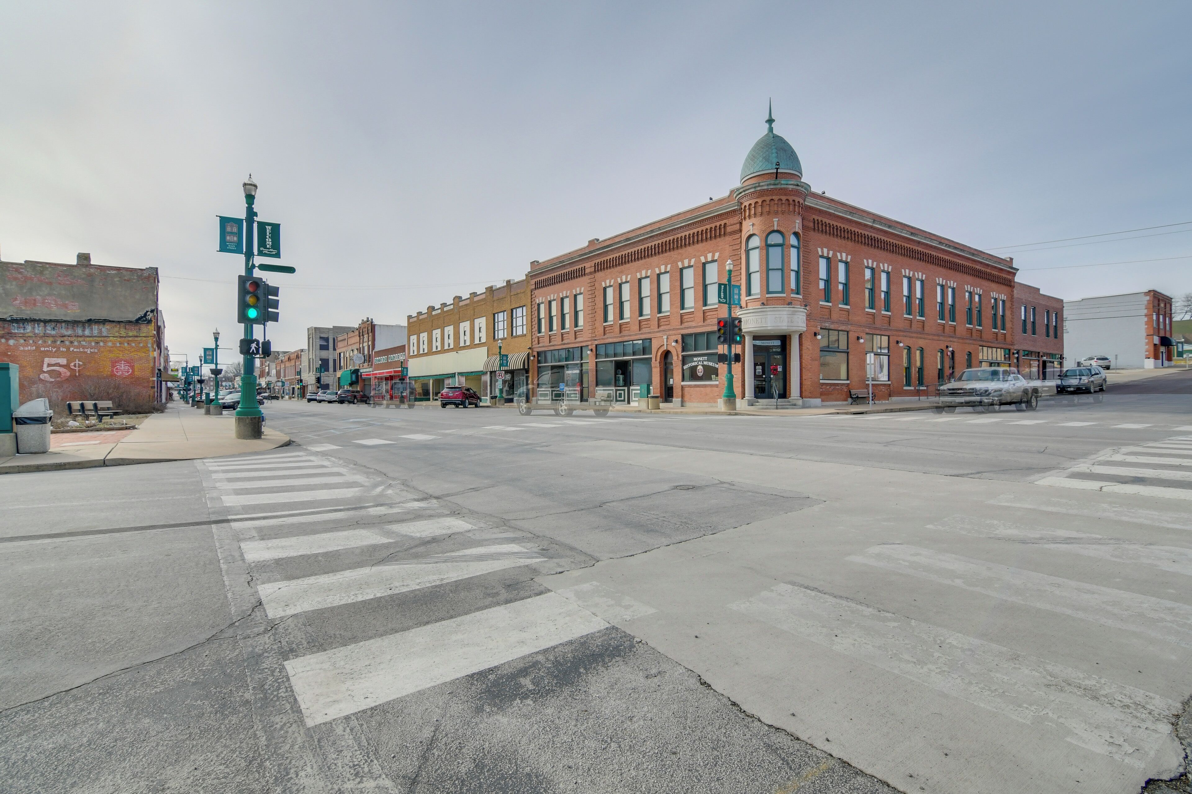 A street intersection with a historic building featuring a dome, a crosswalk, and traffic lights.