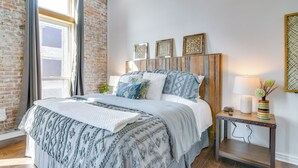 Un dormitorio con una cama grande, cabecera de madera y una mesita de noche con lámpara y objetos decorativos.