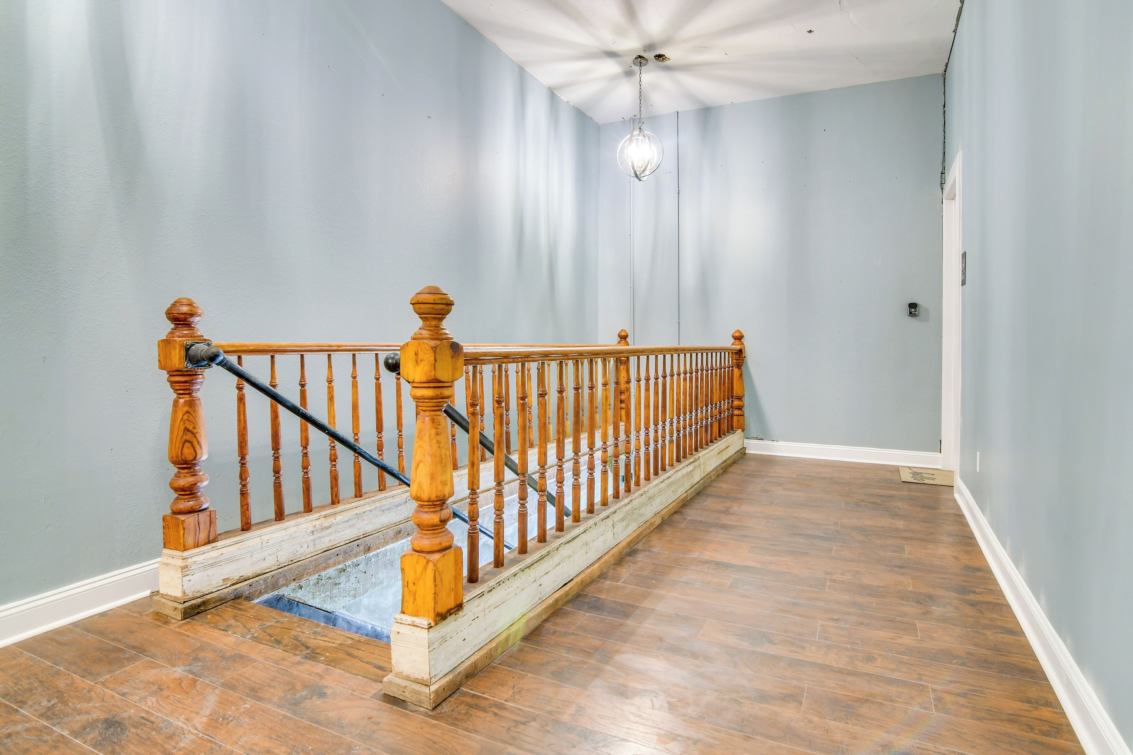 A staircase with wooden balusters and a handrail, leading to a landing with a light fixture.