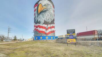 A large mural of an eagle with an American flag design at its base, located in an open field with a sign for the Freedom Silo nearby.