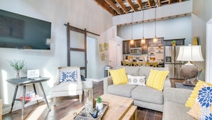 A modern living room with a sofa, coffee table, and a TV. - Dtwn Loft in the Heart of Monett: Pets Welcome! (Monett)