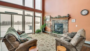 A spacious living room with a fireplace, large windows, and a cozy seating area. - The Gathering Place: Rushville Home w/ Hot Tub (Rushville)