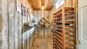 A narrow, rustic hallway with wooden walls and a wooden wine rack on the right. - The Gathering Place: Rushville Home w/ Hot Tub (Rushville)