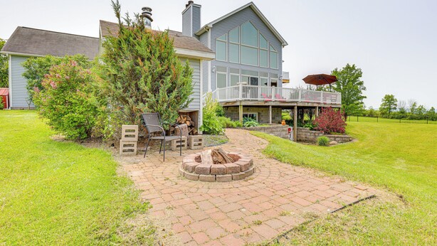 A house with a patio area featuring a fire pit, outdoor furniture, and a covered deck with an umbrella. - The Gathering Place: Rushville Home w/ Hot Tub (Rushville)
