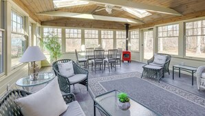 A sunlit patio with wicker furniture, a glass table, and a ceiling fan. - Beach & Golf Hub w/ All-season Sunroom in Cape Cod (Orleans)