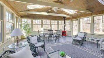 A sunlit patio with wicker furniture, a glass table, and a ceiling fan.