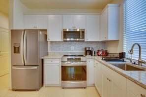 A modern kitchen with stainless steel appliances, white cabinetry, a granite countertop, and a built-in oven. - 1 Mi to Heritage Lake Park: Duplex w/ Patio! (Menifee)