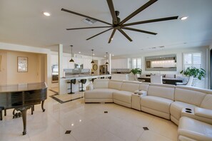 A spacious living room with a piano, a large L-shaped sectional sofa, and a ceiling fan. - Luxurious & Spacious Family Duplex in Menifee! (Menifee)