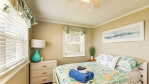 A bedroom with a bed, a nightstand, a lamp, a window with blinds, and a wall-mounted painting. - Swim, Fish & Explore! Family Hague Haven w/ Dock (Hague)