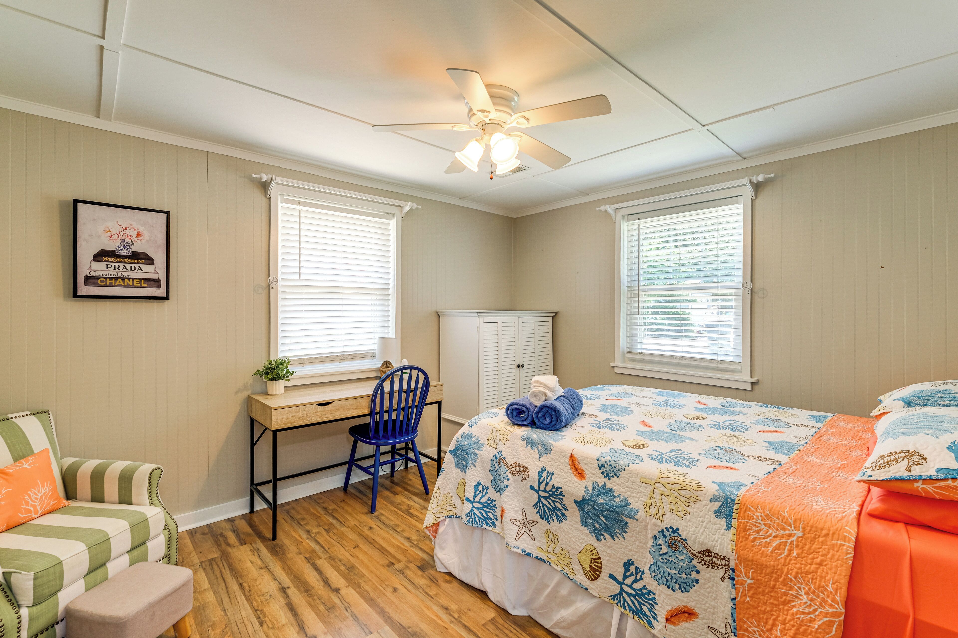 A bedroom with a bed, a desk, a chair, a wardrobe, and a ceiling fan.
