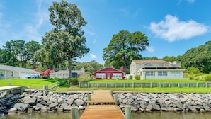 A wooden dock leading to a house with a red roof, surrounded by a stone wall and greenery. - Swim, Fish & Explore! Family Hague Haven w/ Dock (Hague)