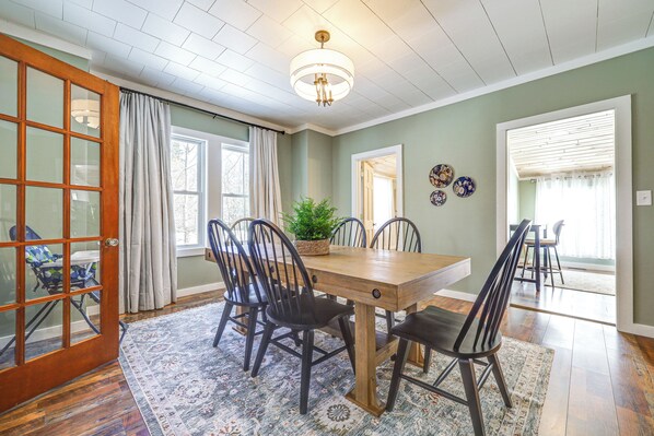 A dining room with a wooden table and chairs, a chandelier, and a view of the outdoors through a window. - 15 Mi to Canadian Border: Home w/ Yard! (Houlton)