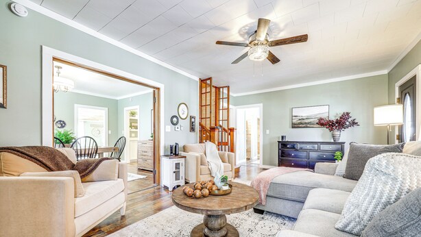 A spacious living room with a large mirror, a ceiling fan, and a round wooden coffee table. - < 1 Mi to Houlton Riverfront Park: Home w/ Yard! (Houlton)