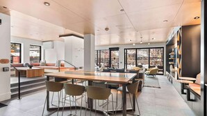 Een modern interieur met een centrale eettafel, zitplaatsen en een trap naar een hoger niveau.