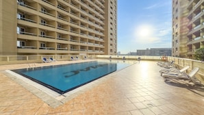 A rooftop swimming pool with sun loungers and a view of high-rise buildings. - FIRST CLASS | Studio | Cozy & Chic Retreat (Dubai)