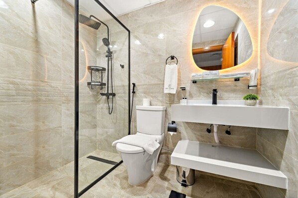 Un baño moderno con ducha de vidrio, inodoro y tocador con espejo.