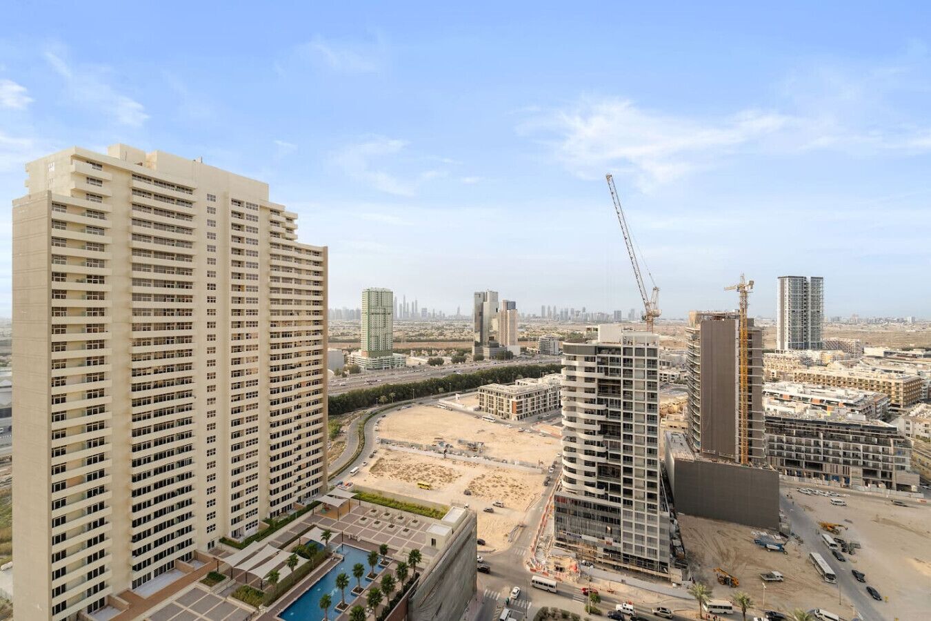 A high-rise residential building with multiple floors, a swimming pool, and a view of the cityscape in the background.