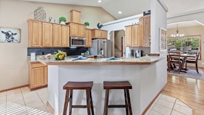 Une cuisine avec des meubles de rangement en bois, un îlot central doté de tabourets, un four à micro-ondes et un réfrigérateur.
