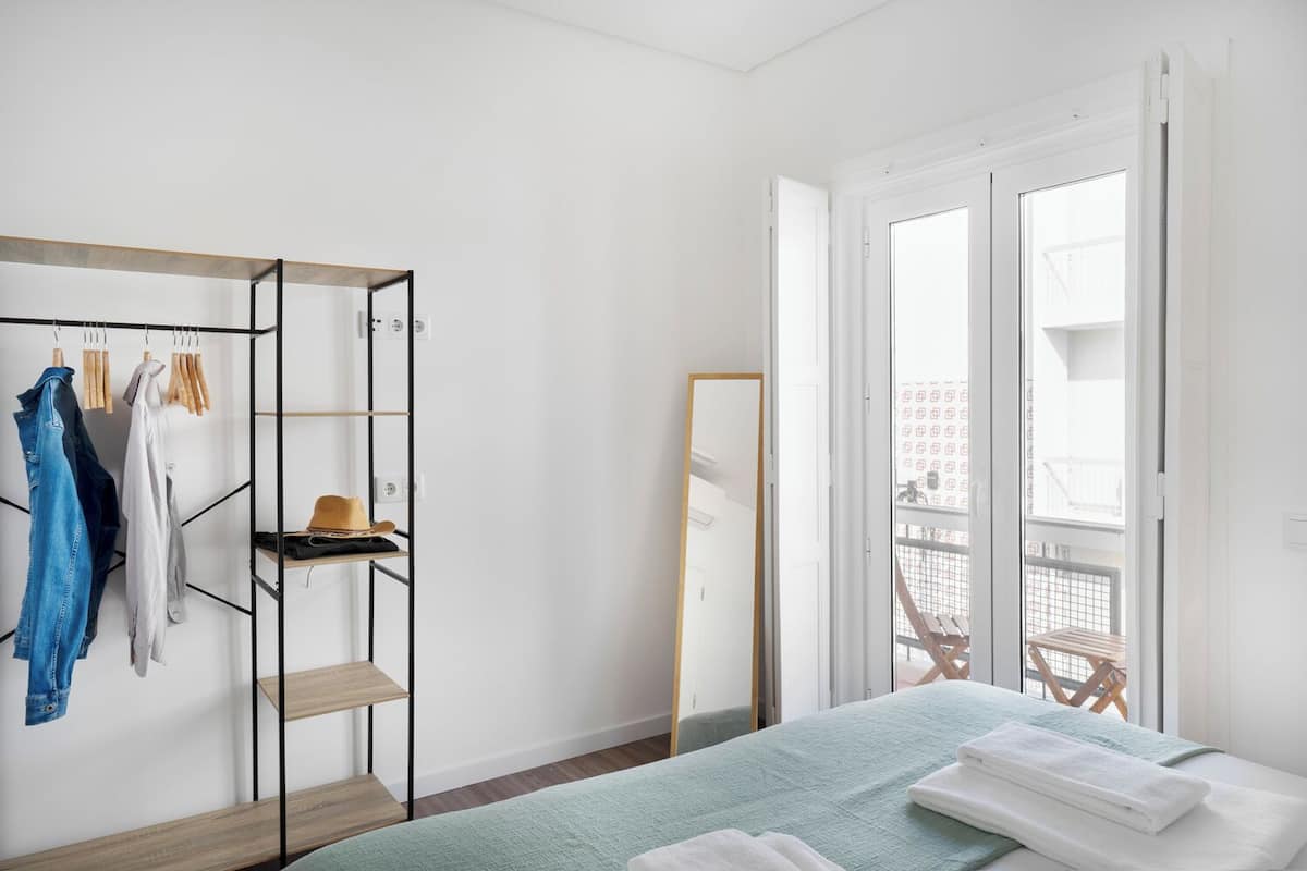 A bedroom with a bed, a wardrobe, and a balcony with a view.
