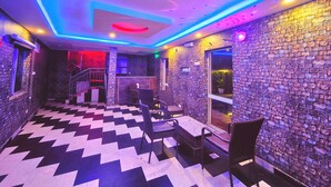 A room with a checkered floor, stone walls, and a staircase leading to an upper level.