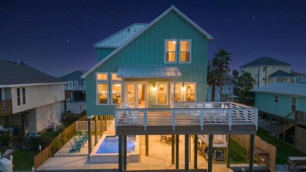 Una casa frente al agua con piscina, terraza y zona cubierta.