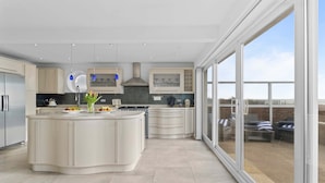 A modern kitchen with a large island, built-in appliances, and a view of the outdoor patio.