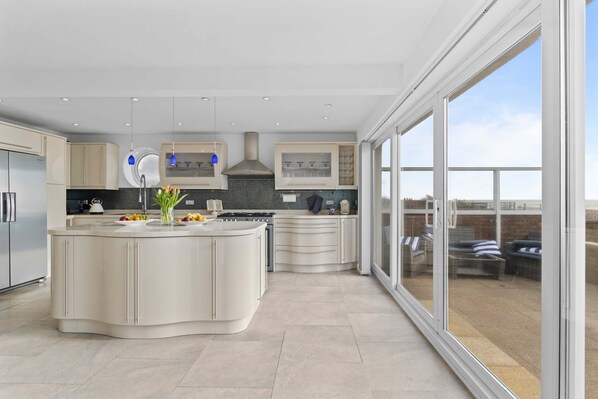 A modern kitchen with a large island, built-in appliances, and a view of the outdoor patio.