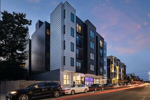 A modern multi-story building with a European Wax Center sign, featuring a mix of dark and light facades, and a street with cars and light trails. - Philly s Coolest Cozy (Philadelphia)