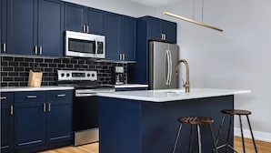 A modern kitchen with dark blue cabinets, stainless steel appliances, and a white countertop. - Philly s Coolest Cozy (Philadelphia)