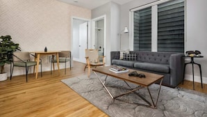 Un salon moderne avec un canapé gris, une table basse en bois et un coin repas comprenant une table et des chaises.