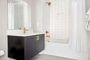 A modern bathroom with a white sink, gold faucets, and a black vanity. - Philly A Colorful Urban Oasis (Philadelphia)