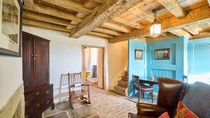 Ein rustikales Interieur mit freiliegenden Holzbalken, einem Holzschrank, einem gemusterten Teppich und einer blauen Tür.