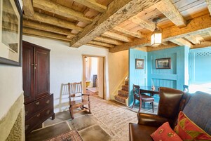 A rustic interior with exposed wooden beams, a wooden cabinet, a patterned rug, and a blue door.