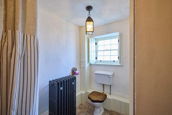 A bathroom with a radiator, a toilet, a window, and a hanging light fixture. - Host Stay Drovers Rest (Stanley)