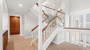 A modern interior with a wooden staircase, white walls, and a view of the outside. - Waterfront Retreat With Stunning Views Modern Co (Santa Ana)
