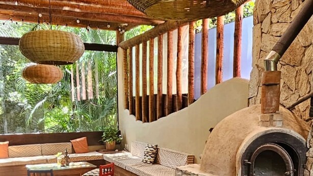 An outdoor seating area with stone flooring, a stone fireplace, and hanging woven light fixtures. -  Casa Cacau Buzios (Búzios)